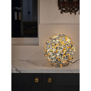 Round, multicolored glass globe lamp in a room with a black door and white walls.