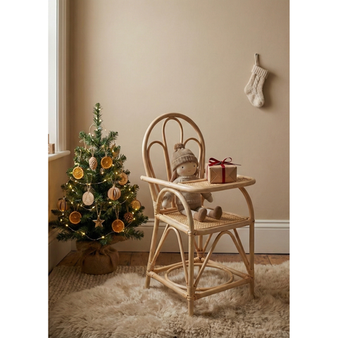 Wooden high chair with a teddy bear and small gift, Christmas tree with decorations in a room.