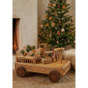 Wooden toy cart with Christmas decorations in front of a decorated tree and fireplace.