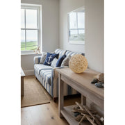 Living room with striking shell lamp, striped sofa, decorative pillows, and a wooden coffee table.