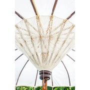 Close-up view of the intricate woven thread detail beneath the white parasol canopy, showing the bamboo ribs and central wooden peg.