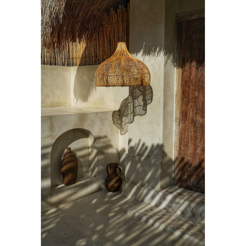 Scalloped lamp shade surrounded by wood and neutral tones in rustic villa setting by Collectiviste lighting UK.