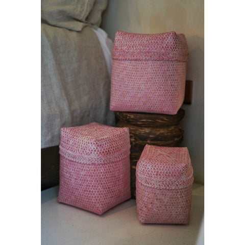 Set of three pink storage baskets in bedroom setting.