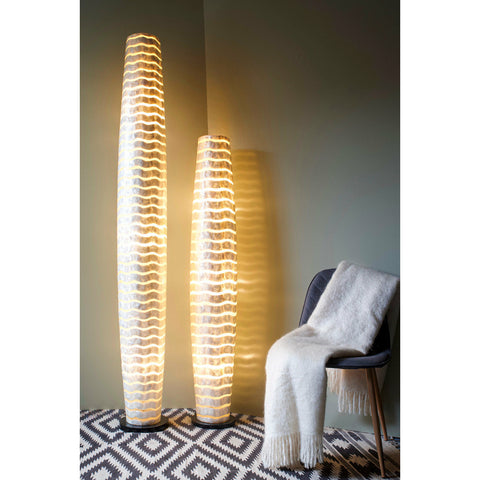 Tall white floor lamps with wave motif on monochrome carpet. Shell lighting by Collectiviste.