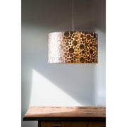 Gold drum light shade hanging over wooden table.